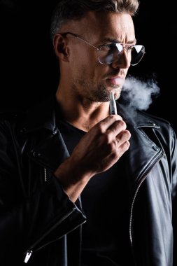 Kyiv, Ukrayna - 11 Ekim 2019: Siyah üzerine izole edilmiş sigara içen deri ceketli yakışıklı adam