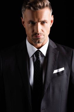 Yakışıklı iş adamı siyah kameraya bakıyor.