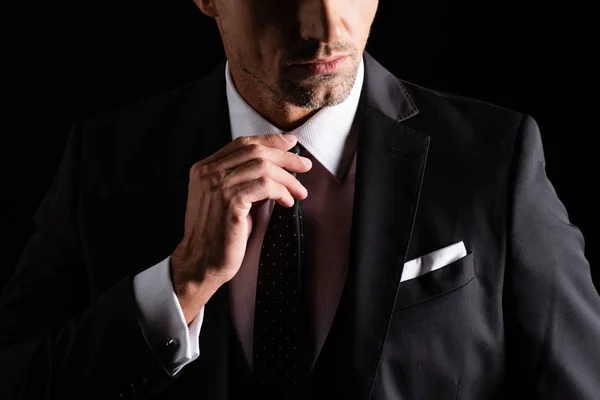 黒で隔離されたネクタイを調整するビジネスマンの作物ビュー — ストック写真