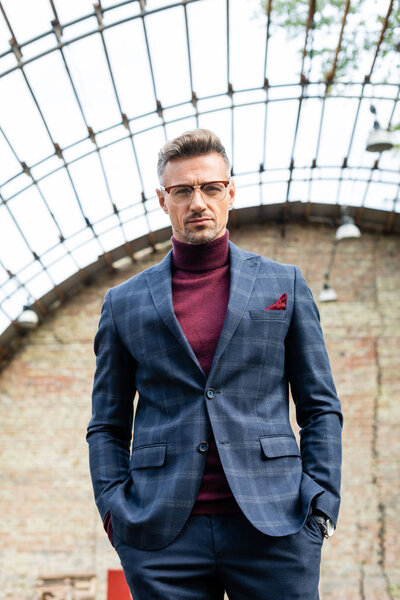 Красивый бизнесмен в очках смотрит в камеру на улице
 