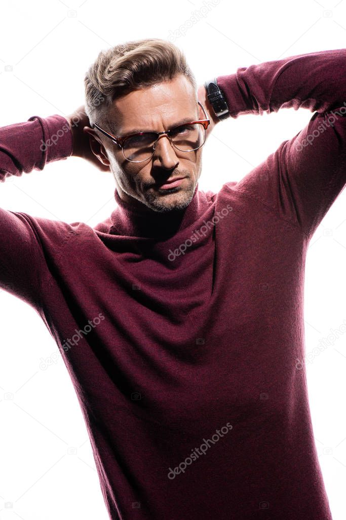 Serious man with hands behind head looking at camera isolated on white 