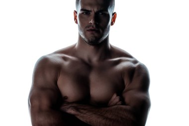 sexy muscular bodybuilder with bare torso posing with crossed arms in shadow isolated on white clipart