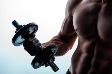 Çıplak gövdeli seksi kaslı vücut geliştiricinin kesikli görüntüsü. Beyaz halterle egzersiz yapıyor.