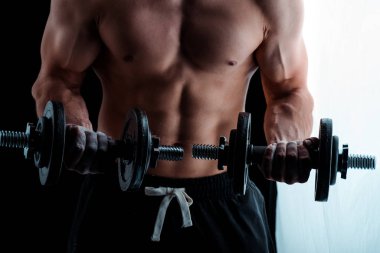 cropped view of sexy muscular bodybuilder with bare torso exercising with dumbbells clipart