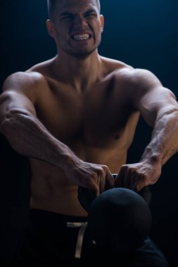 Siyah arka planda kettlebell ile çıplak gövde kesen gergin seksi kaslı vücut geliştirici