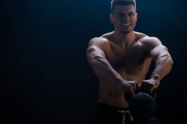 Siyah arka planda kettlebell ile çıplak gövde kesen gergin seksi kaslı vücut geliştirici