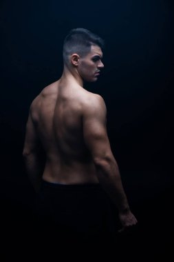 back view of sexy muscular bodybuilder with bare torso posing isolated on black clipart
