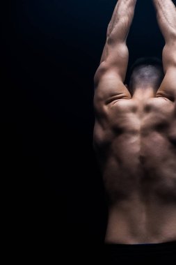 Siyah üzerinde çıplak vücut pozu veren seksi kaslı vücut geliştiricinin arka planı