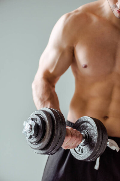 cropped view of sexy muscular bodybuilder with bare torso exercising with dumbbell isolated on grey