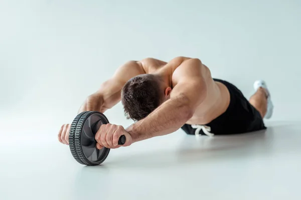 Sexy muscular bodybuilder with bare torso exercising with ab wheel on grey background — Stock Image Sexy Muscular Bodybuilder Bare Torso Exercising Wheel Grey Background Royalty Free Stock Photos