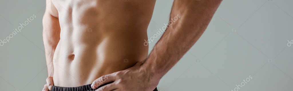 Cropped view of sexy muscular bodybuilder with bare torso posing with hands on hips isolated on grey, panoramic shot — Stock Image Cropped View Sexy Muscular Bodybuilder Bare Torso Posing Hands Hips Stock Picture