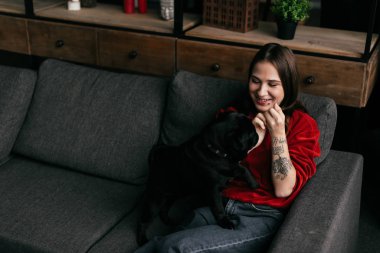 Oturma odasında pug 'la oynayan gülümseyen kız.