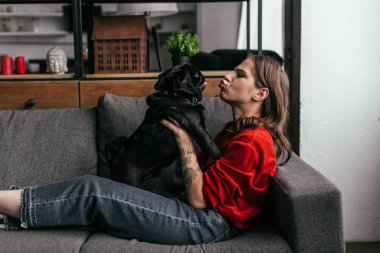 Çekici bir kadının kanepede köpeğe somurtması. 