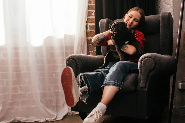 Lächelnde Junge Frau Mit Beinprothese Spielt Hause Mit Mops Sessel — Stockfoto
