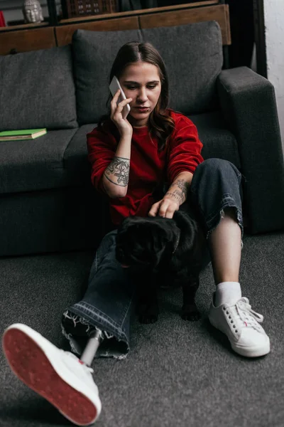 Mulher Com Perna Protética Falando Smartphone Enquanto Acaricia Pug Chão — Fotografia de Stock