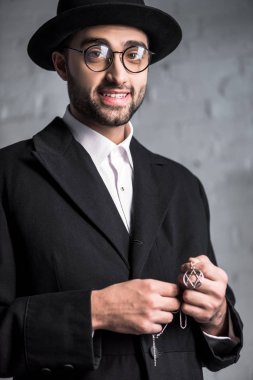 Gözlüklü yakışıklı ve gülümseyen Yahudi adam David kolyesinin yıldızını tutuyor. 
