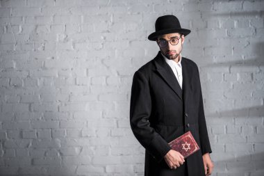handsome and sad jewish man in glasses holding tanakh  clipart