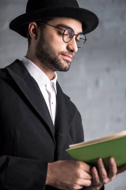 Gözlüklü yakışıklı ve genç Yahudi bir adam kitap okuyor. 