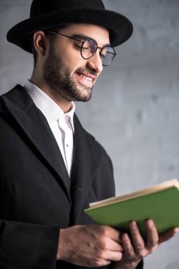 Gözlüklü yakışıklı ve gülümseyen Yahudi adam kitap okuyor. 