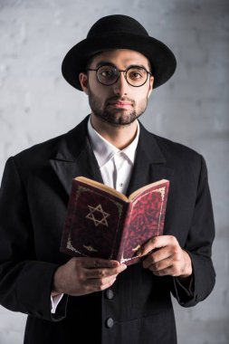 handsome and young jewish man in glasses holding tanakh  clipart