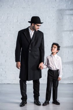 Gülümseyen Yahudi baba ve tatlı oğul el ele tutuşup birbirlerine bakıyorlar. 