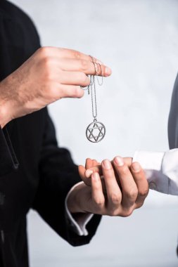 cropped view of jewish father giving star of david necklace to son  clipart