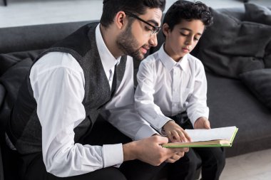 Yakışıklı Yahudi baba ve oğul evde kitap okuyorlar. 
