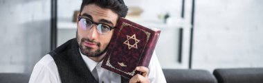 panoramic shot of handsome jewish man in glasses holding tanakh  clipart