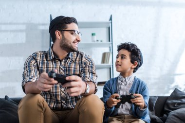 Kyiv, Ukrayna - 15 Ekim 2019: gülümseyen Yahudi baba joystick 'i tutuyor ve oğluna bakıyor 
