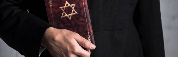 panoramic shot of young jewish man holding tanakh 