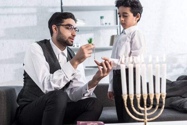 jewish father giving necklace to cute son in apartment 