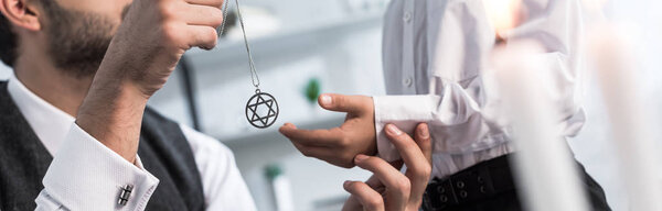 panoramic shot of jewish father giving star of david necklace to son in apartment 