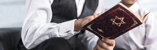 panoramic shot of jewish father and son reading tanakh in apartment 