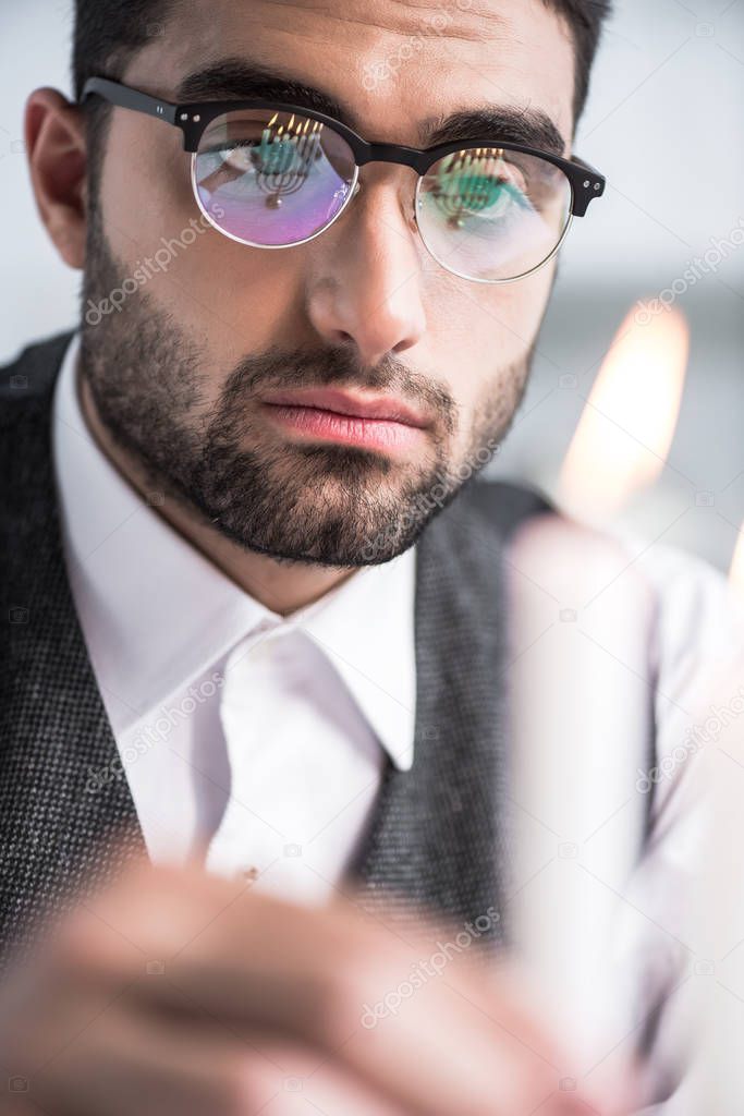 selective focus of handsome jewish man in glasses holding candle 