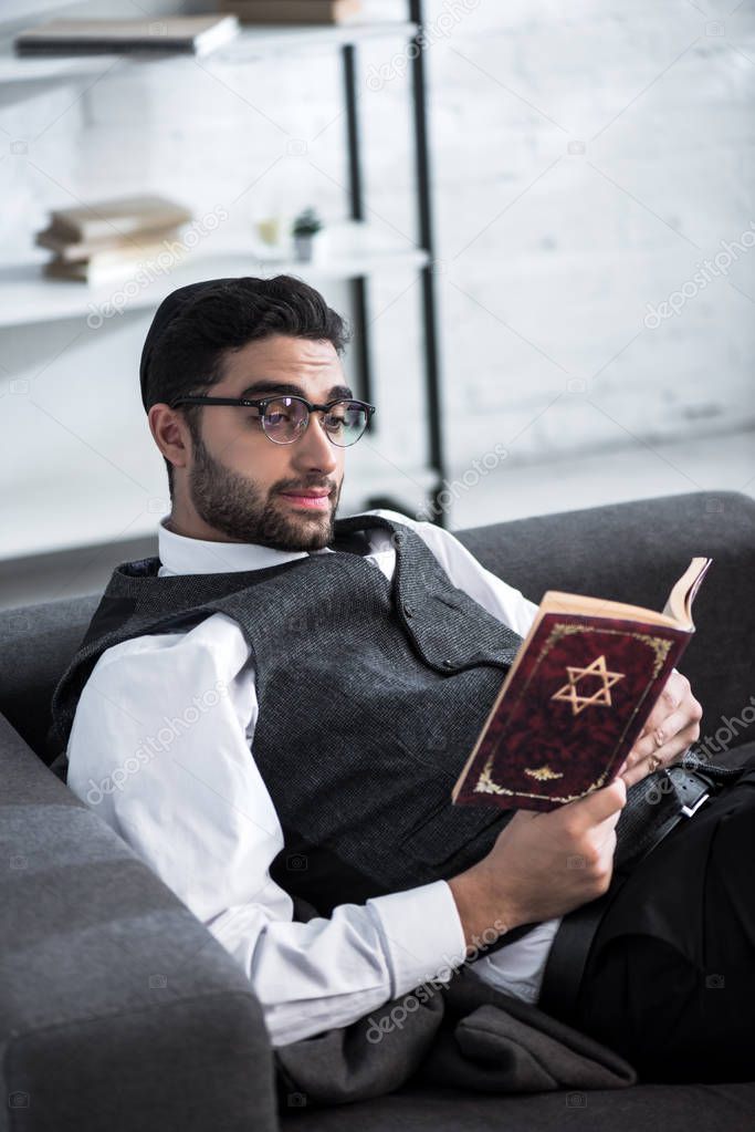 handsome and young jewish man in glasses reading tanakh 