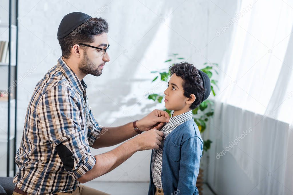 side view of smiling jewish father looking at son in apartment 