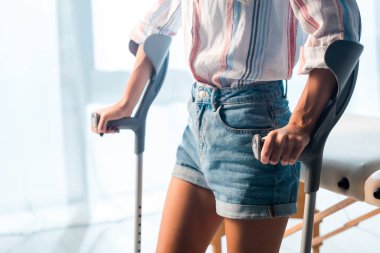 Klinikte koltuk değneği tutan kırık bir kadın görüntüsü. 