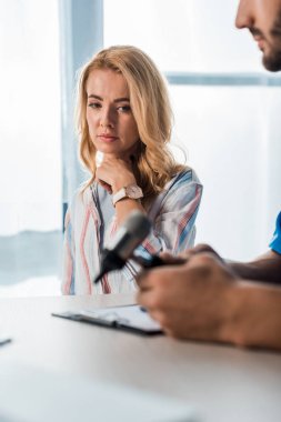 selective focus of woman looking at otoscope in hands of bearded doctor  clipart