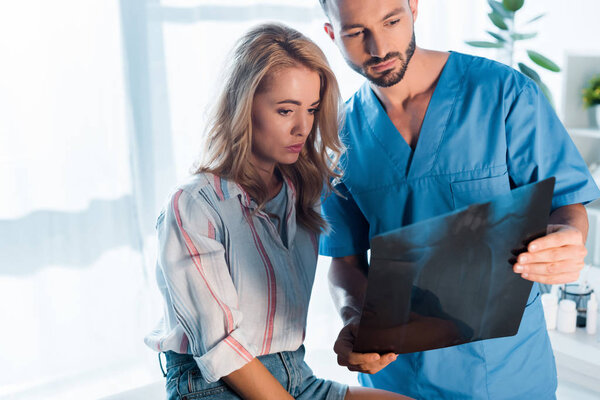 handsome orthopedist and attractive woman looking at x-ray 