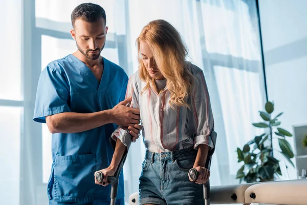 Guapo Médico Pie Cerca Mujer Con Muletas — Foto de Stock