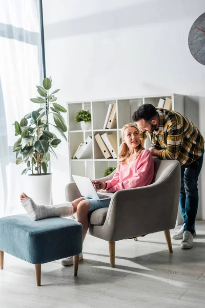 Skäggig Man Står Nära Skadad Kvinna Som Arbetar Hemifrån Med — Stockfoto