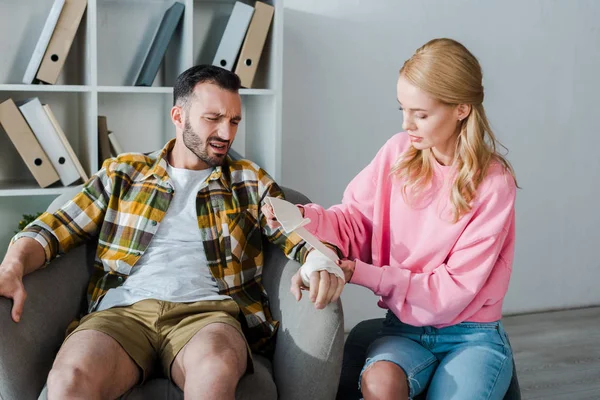 Caring Woman Putting Bandage Injured Hand Bearded Man — Stok fotoğraf