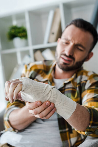 selective focus of injured arm of bearded man suffering from pain 
