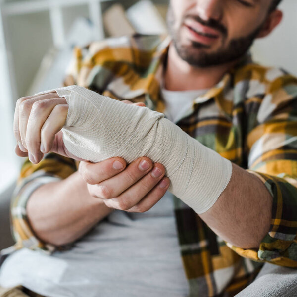 selective focus of injured hand of man in bandage 