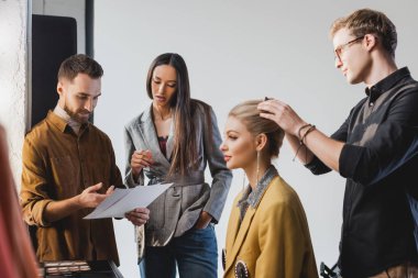 Yapımcı ve fotoğrafçı konuşuyor ve kuaför kuliste modellik yapıyor.  