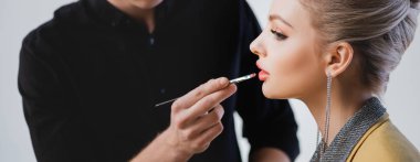 panoramic shot of Makeup Artist doing makeup to stylish model on backstage clipart