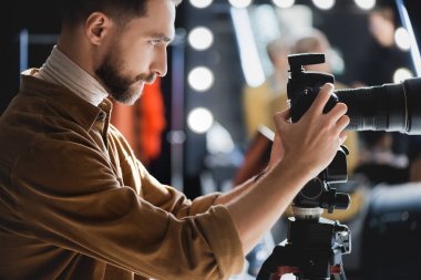 Sahne arkasında dijital kamerayla fotoğraf çeken fotoğrafçının yan görüntüsü