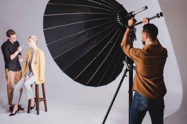 Sahne arkasındaki yansıtıcıya dokunan fotoğrafçının seçici odağı ve makyaj sanatçısı modelden modele makyaj yapıyor. 