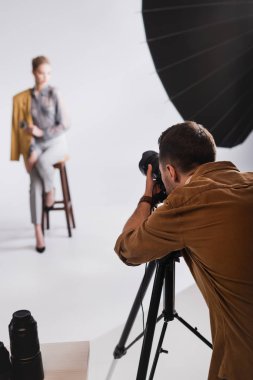 selective focus of photographer taking photo with digital camera of model on backstage clipart