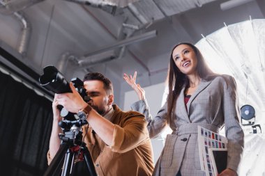 Fotoğrafçının sahne arkasında fotoğraf çektiği ve yapımcının gülümsediği düşük açılı görüntü 